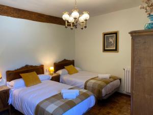 a bedroom with two beds and a chandelier at Casa Rural Masión de Egüés in Elcano