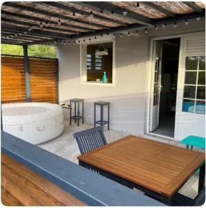 a patio with a hot tub and a wooden table at Le belair in Le Diamant