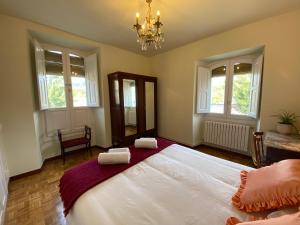 a bedroom with a large white bed and windows at Casa Rural Masión de Egüés in Elcano