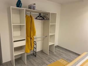 a walk in closet with white shelves and a yellow robe at Le belair in Le Diamant
