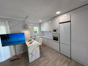 a kitchen with white cabinets and a desk with a monitor at ThE WHALE HOUSE in El Campello