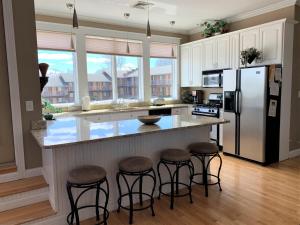 a kitchen with a counter with stools and a refrigerator at Pier Harbor #2 in Saint Ignace