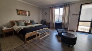 a bedroom with a bed and a table and a chair at Stay at 64 Omeya in Windhoek