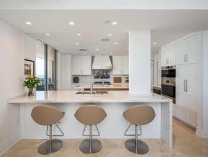 Una cocina con gabinetes blancos y una gran isla con dos taburetes. en Condo With Ocean & Intracoastal Views, en Hollywood Beach