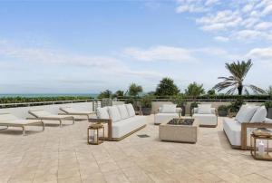 a patio with white chairs and tables on a roof at Southeast Oceanfront Residence in Hollywood Beach