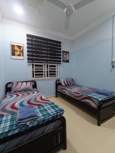 Un dormitorio con dos camas y una ventana. en ABE Homestay Gong Badak, en Kuala Terengganu 3 fotos más