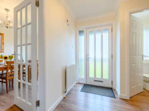 a hallway with a door leading to a dining room at Seaglass House in Beadnell
