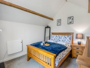 Un dormitorio con una cama de madera y una mesita de noche. en The Barn, en Martham