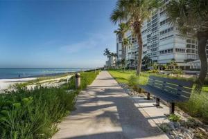 a park bench next to a beach with a building at Spacious Gulf-view Residence in Naples