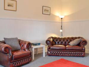 two brown leather chairs and a table with a lamp at The Bothy - Uk33907 in Rattray