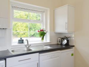 a white kitchen with a sink and a window at The Bothy - Uk33907 in Rattray