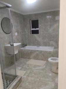 Un baño con bañera, inodoro y lavabo. en Lemon Lodge, en Parow