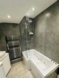 ein Badezimmer mit Badewanne, Dusche und Waschbecken in der Unterkunft Northcliffe - Stylish Stone Cottage - Spa Bath - Peak Views in Bradwell