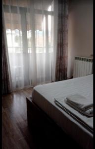 a bedroom with a bed and a window with curtains at Hotel Sfinks in Elbasan