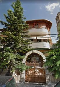 a building with a gate and a tree in front of it at Hotel Sfinks in Elbasan