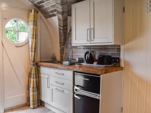 a kitchen with white cabinets and a black refrigerator at The Orb in Hastingleigh