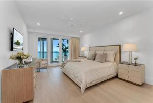 a white bedroom with a bed and a desk and chairs at Gulf-front Masterpiece in Naples +14 photos