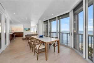 a dining room with a table and chairs and windows at Gulf-front Masterpiece in Naples