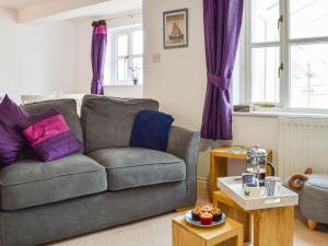 a living room with a gray couch and purple pillows at Primrose Cottage in Little Rissington