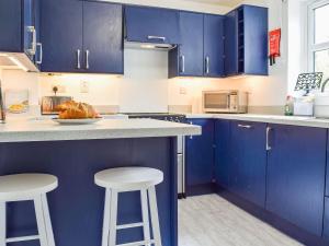 a kitchen with blue cabinets and white counter tops at Primrose Cottage in Little Rissington +12 photos