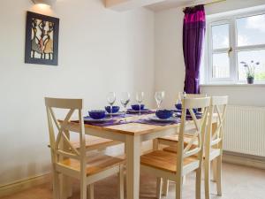 a dining room table with chairs and wine glasses at Primrose Cottage in Little Rissington