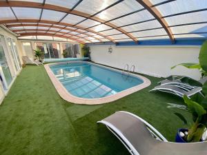an indoor swimming pool with a retractable roof at Nature, évasion, jacuzzi, grande piscine et cinéma in Houdancourt
