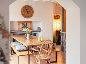 ein Esszimmer mit einem Tisch und Stühlen sowie einer Uhr an der Wand in der Unterkunft Dee Bank Cottage in Llangollen