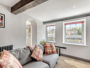ein Wohnzimmer mit einem grauen Sofa und 2 Fenstern in der Unterkunft Dee Bank Cottage in Llangollen