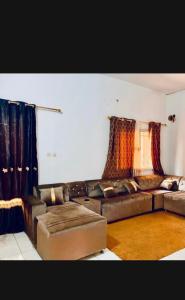 - un salon avec un canapé en cuir brun et des rideaux dans l'établissement MandéHabitat, à Bamako