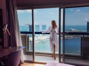 a woman in a white dress standing in front of a window at Swissotel The Stamford Singapore in Singapore