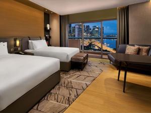 a hotel room with two beds and a desk and a window at Swissotel The Stamford Singapore in Singapore +214 photos
