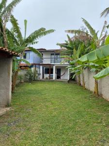 a house with palm trees in front of a yard at Casa para relaxar a 600 M da Praia do Paí Vitório in Búzios