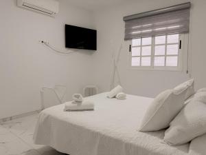 een witte slaapkamer met een bed met handdoeken erop bij Alcalá Retreat: Ocean View & Modern Comfort in Alcalá