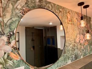 a mirror on a bathroom wall with a mural of flowers at Zentrales Studio-Appartment mit Terrasse in Hildesheim
