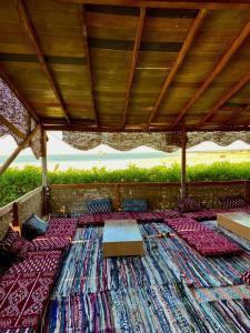 a covered patio with a table and chairs and a large rug at كامب واحة الغروب in Dār as Salām