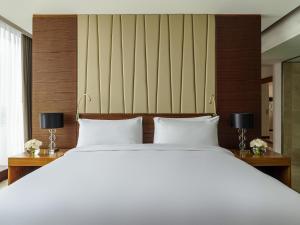 une chambre avec un grand lit blanc avec deux lampes dans l'établissement Fairmont Bab Al Bahr, à Abu Dhabi