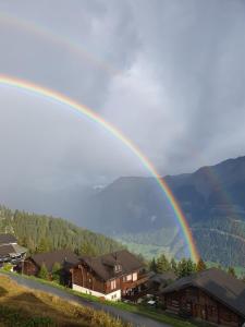 a rainbow in the sky over a town with houses at Tamara Parterre in Riederalp