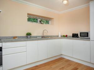 a kitchen with white cabinets and a sink at 1 The Folly's - Uk45189 in Abbotskerswell