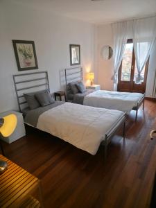 Dos camas en una habitación con dos mesas. en Langhe Bee Home, en Cravanzana