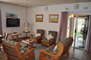 a living room with chairs and a flat screen tv at Cottage Glen Lorne in Gaborone