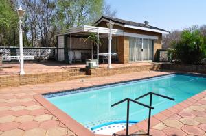 a swimming pool in front of a house at Cottage Glen Lorne in Gaborone