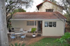 a small white house with chairs and a table at Cottage Glen Lorne in Gaborone