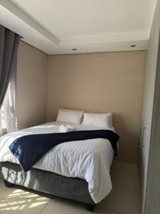 a bedroom with a bed with white sheets and a window at Cozy Central BNB in Mbabane +2 photos
