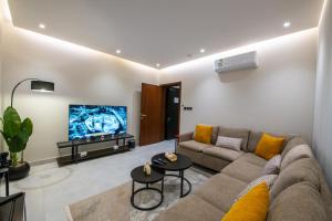 a living room with a couch and a flat screen tv at Mabaat-Deluxe 1BR Al Waha 621 in Jeddah +11 photos