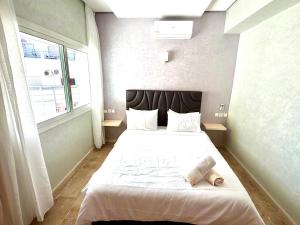 a bedroom with a large white bed with a window at Reda's Apparts centre ville wifi 200 Mo in Fès