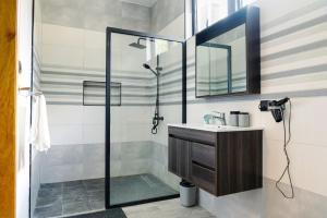 a bathroom with a shower with a sink and a mirror at Villa Soleil de L'est in Port Mathurin