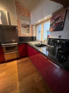 cocina con armarios rojos y encimera negra en The Chalet - in the heart of Metz, en Metz 7 fotos más
