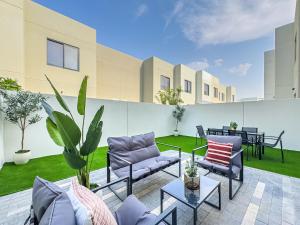 eine Terrasse mit Sofas und Tischen auf einem Gebäude in der Unterkunft Amazing Townhouse - Yas Island - 5 min to Formula 1, Ferrari World, Warner Bros, Sea World - Designer's Choice in Abu Dhabi