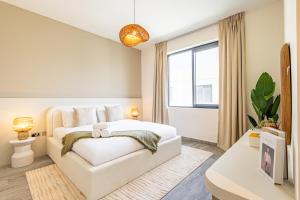 ein Schlafzimmer mit einem weißen Bett und einem Fenster in der Unterkunft Amazing Townhouse - Yas Island - 5 min to Formula 1, Ferrari World, Warner Bros, Sea World - Designer's Choice in Abu Dhabi