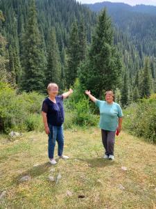 two women standing on a hill with their arms up at Kf guest house 2 in Shabdan +7 photos